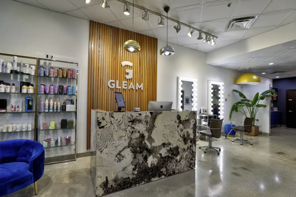 Gleam Hair Studio's front desk with marble reception counter, logo and styling stations