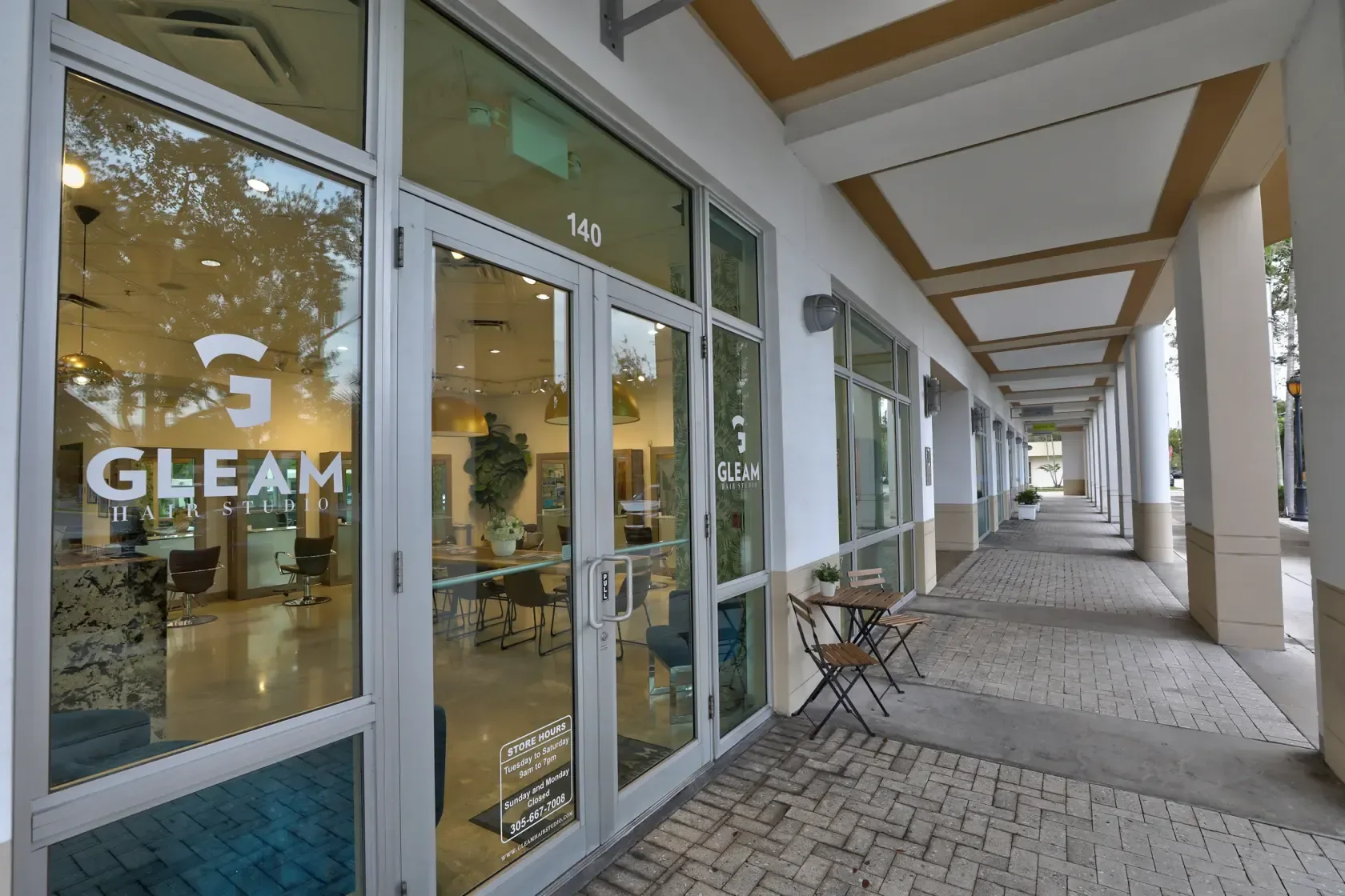 Glass entrance to Gleam Hair Studio along a South Miami shopping walkway