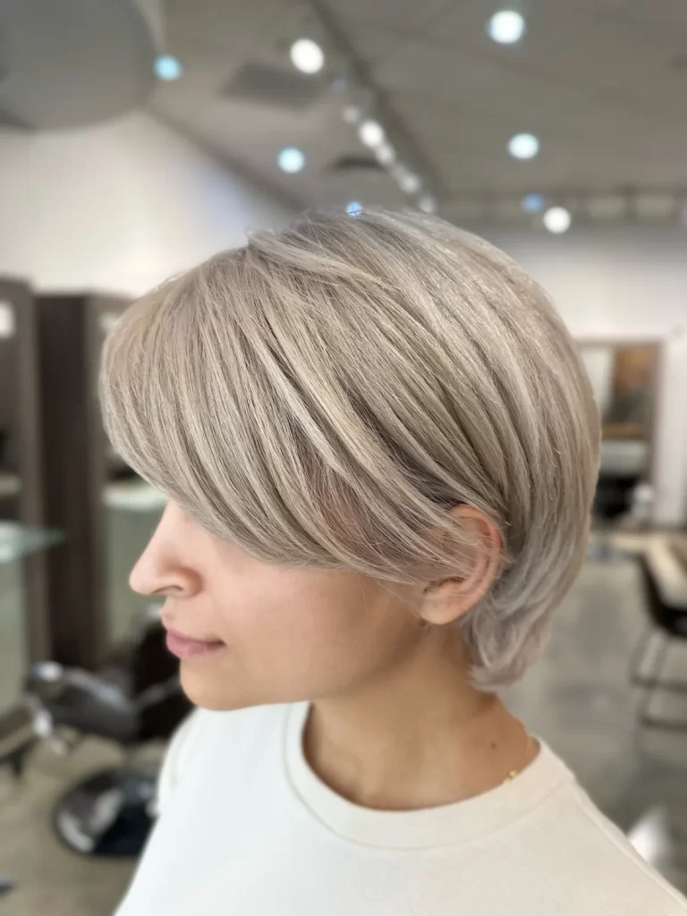 Short layered blonde pixie haircut with side-swept fringe at Gleam Hair Studio in South Miami